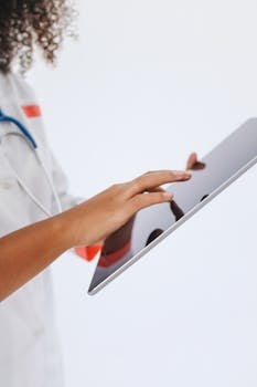 Close-up of a doctor using a tablet for medical records in a professional setting.