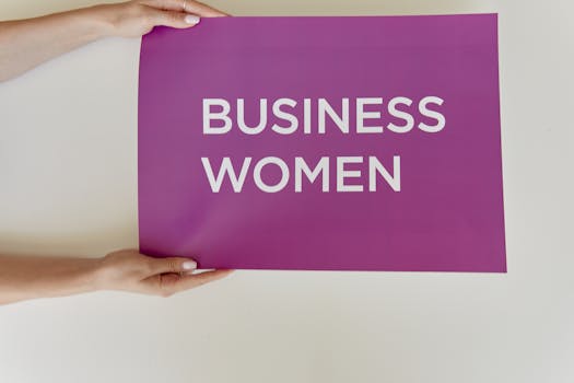 Hands holding a purple sign with 'Business Women' for empowerment.