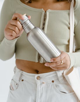 Person holding a reusable stainless steel water bottle promoting eco-friendly and zero waste lifestyle.