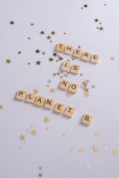 Scrabble tiles on a white background spell 'There is No Planet B' surrounded by star confetti.