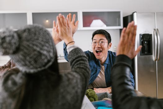 A diverse group of adults sharing a celebratory high five in a modern kitchen setting.