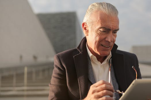 Senior businessman with tablet outdoors, adjusting eyeglasses, and reviewing business data.